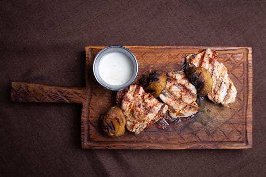 grilled chicken fillet with mushrooms on a wooden board top view.