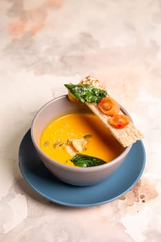 bright yellow pumpkin soup with seeds in a plate on the table.