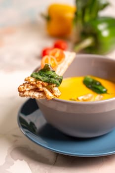 bright yellow pumpkin soup with seeds in a plate on the table.