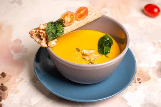 bright yellow pumpkin soup with seeds in a plate on the table.