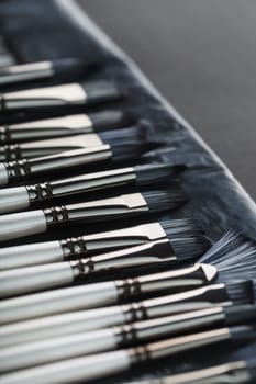 Paint tubes, brushes for painting and palette knifes on old wooden background. Close-up