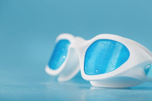 White swimming goggles on a blue background in a minimalist style with free space