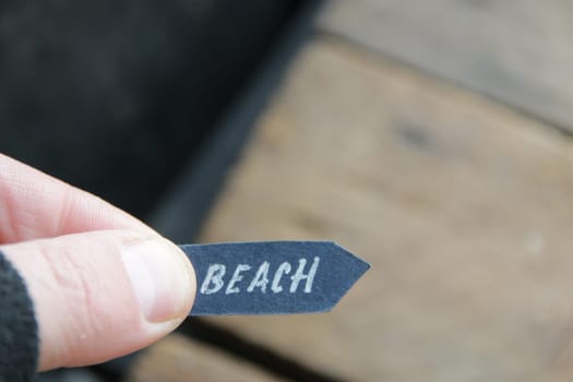 Beach idea. A hand holds a pointer with the inscription beach on a vintage background.