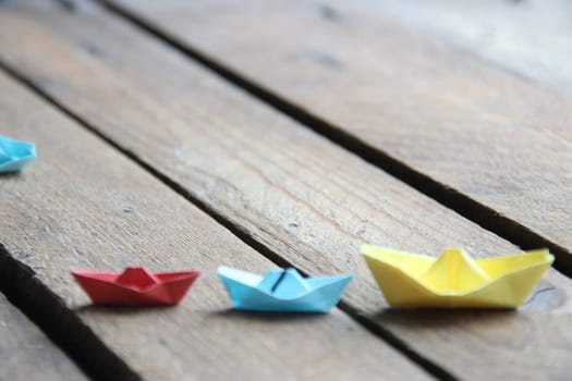 leadership concept. Paper boats on vintage wooden background.