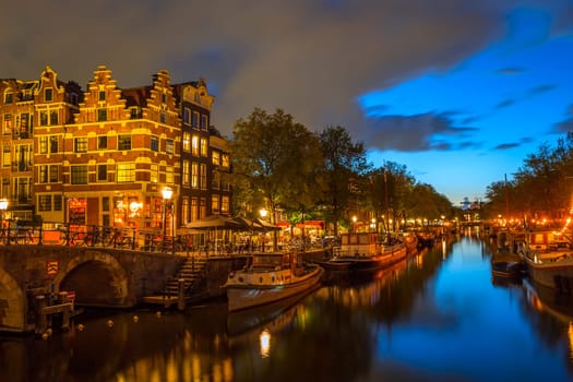 Netherlands. Evening embankment of Amsterdam. Stone bridge, bicycles near the fence and houseboats