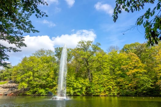 Sunny summer day in the Ukrainian park in the city of Uman. Fountain in the center of a small pond