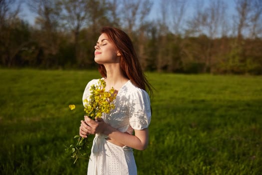 portrait of a beautiful woman with a bouquet of buttercups in her hands in a white dress in nature. High quality photo