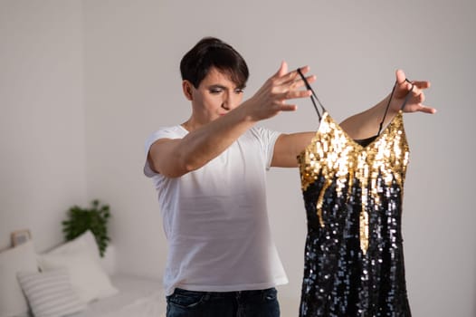 Gay trying on a shiny dress. The transgender chooses the outfit for the party