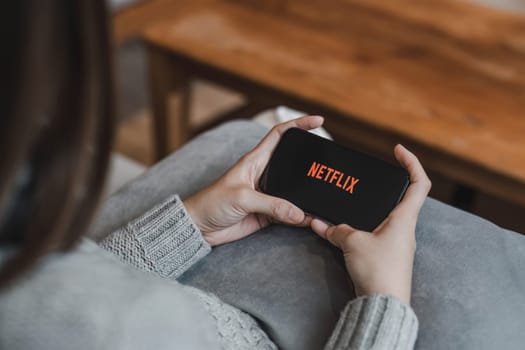 CHIANG MAI, THAILAND, APR 17, 2022: Woman hand holding Smart Phone with Netflix logo on Apple iPhone 14. Netflix is a global provider of streaming movies and TV series...