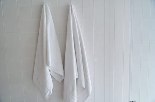 Two white towels hanging in the hotel shower room. High quality photo