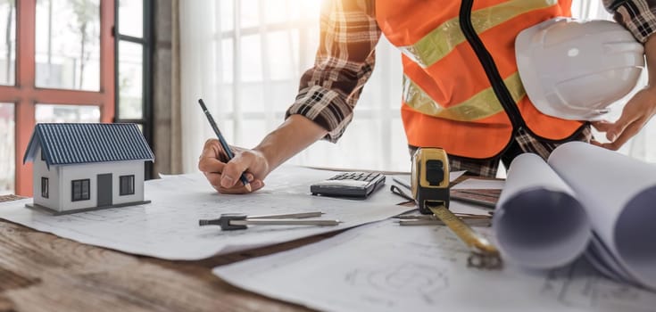 Close up of civil male engineer asian working on blueprint architectural project at construction site at desk in office...