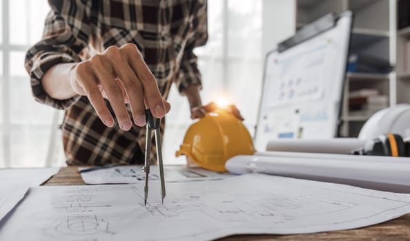 Close up of civil male engineer asian working on blueprint architectural project at construction site at desk in office...