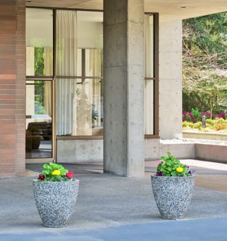 Two small flower beds in front of residential building entrace.