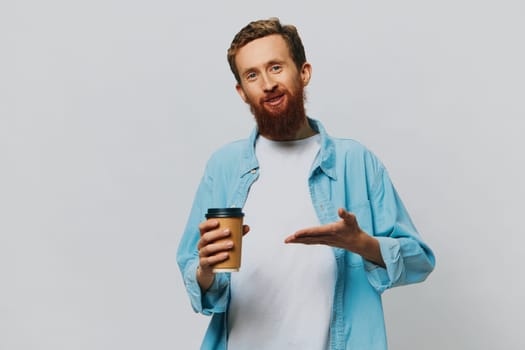 Man hipster with a cup of coffee with a smile on a gray background in a blue shirt and white t-shirt. High quality photo