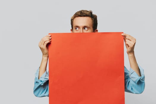 Portrait of an adult male on a gray background with a red piece of paper for your design and text, layout, copy space, space for text. High quality photo