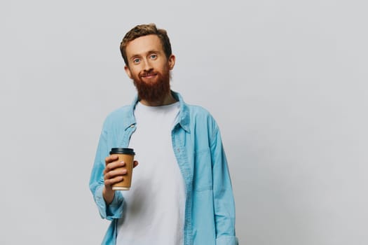 Man hipster with a cup of coffee with a smile on a gray background in a blue shirt and white t-shirt. High quality photo