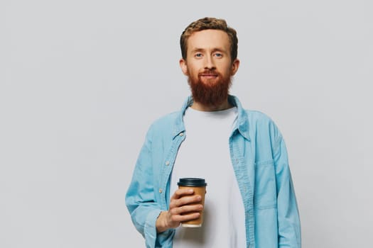 Man hipster with a cup of coffee with a smile on a gray background in a blue shirt and white t-shirt. High quality photo