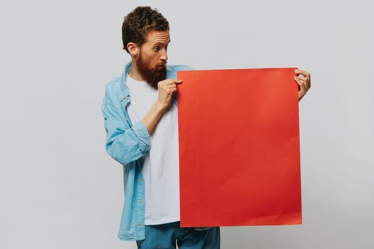 Portrait of an adult male on a gray background with a red piece of paper for your design and text, layout, copy space, space for text. High quality photo