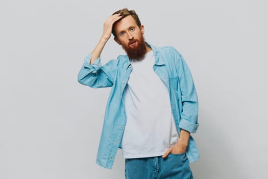 Male hipster portrait smile on gray background in blue shirt and white t-shirt, portrait of a man with a beard. High quality photo