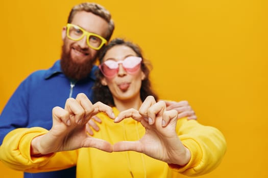 Man and woman couple smiling cheerfully and crooked with glasses, on yellow background, symbols signs and hand gestures, family shoot, newlyweds. High quality photo