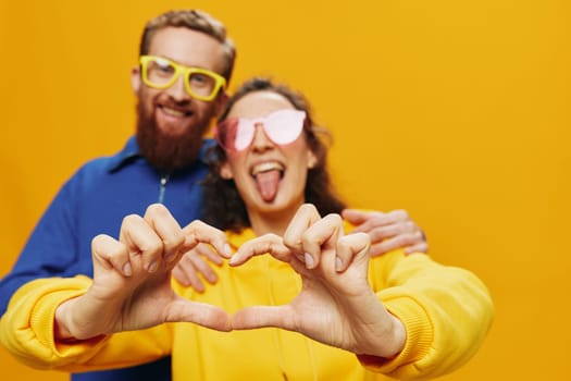 Man and woman couple smiling cheerfully and crooked with glasses, on yellow background, symbols signs and hand gestures, family shoot, newlyweds. High quality photo