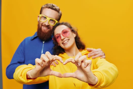 Man and woman couple smiling cheerfully and crooked with glasses, on yellow background, symbols signs and hand gestures, family shoot, newlyweds. High quality photo