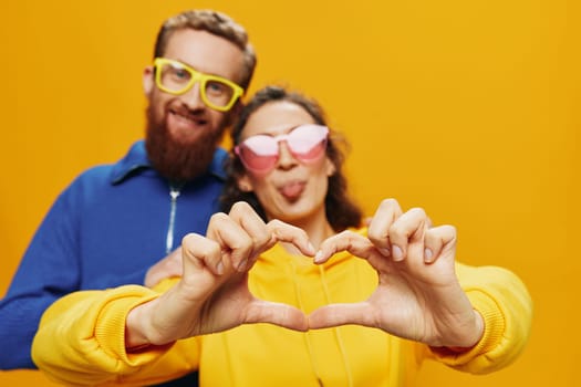 Man and woman couple smiling cheerfully and crooked with glasses, on yellow background, symbols signs and hand gestures, family shoot, newlyweds. High quality photo