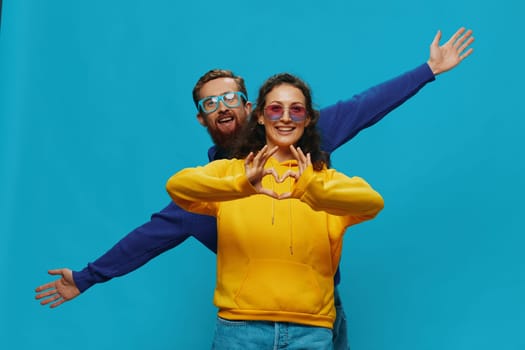A woman and a man fun couple cranking and showing signs with their hands smiling cheerfully, on a blue background, The concept of a real relationship in a family. High quality photo