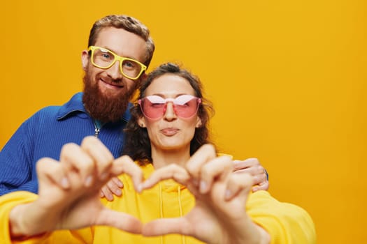 Man and woman couple smiling cheerfully and crooked with glasses, on yellow background, symbols signs and hand gestures, family shoot, newlyweds. High quality photo