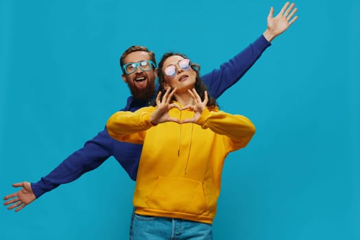 A woman and a man fun couple cranking and showing signs with their hands smiling cheerfully, on a blue background, The concept of a real relationship in a family. High quality photo