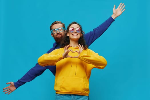 A woman and a man fun couple cranking and showing signs with their hands smiling cheerfully, on a blue background, The concept of a real relationship in a family. High quality photo