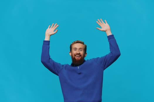 Portrait of a man in a sweater smile and happiness, hand signs and symbols, on a blue background. Lifestyle positive, copy place. High quality photo