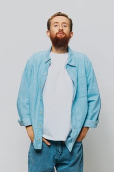 Male hipster portrait smile on gray background in blue shirt and white t-shirt, portrait of a man with a beard. High quality photo