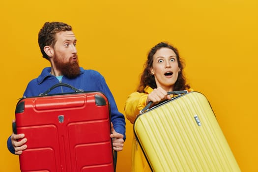 Woman and man smiling, suitcases in hand with yellow and red suitcase smiling merrily and crooked, yellow background, going on a trip, family vacation trip, newlyweds. High quality photo