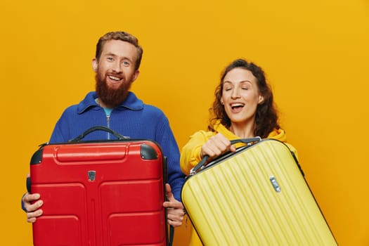 Woman and man smiling, suitcases in hand with yellow and red suitcase smiling merrily and crooked, yellow background, going on a trip, family vacation trip, newlyweds. High quality photo