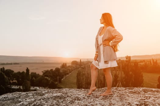 Romantic beautiful bride in white dress posing with sea and mountains in background. Stylish bride standing back on beautiful landscape of sea and mountains on sunset