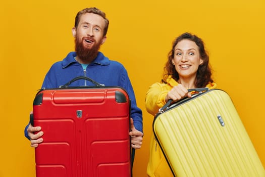 Woman and man smiling, suitcases in hand with yellow and red suitcase smiling merrily and crooked, yellow background, going on a trip, family vacation trip, newlyweds. High quality photo