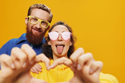 Man and woman couple smiling cheerfully and crooked with glasses, on yellow background, symbols signs and hand gestures, family shoot, newlyweds. High quality photo