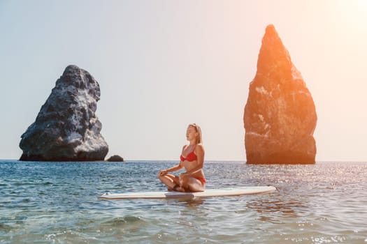 Close up shot of beautiful young caucasian woman with black hair and freckles looking at camera and smiling. Cute woman portrait in a pink bikini posing on a volcanic rock high above the sea