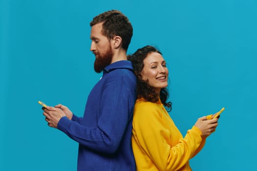 Woman and man cheerful couple with phones in their hands crooked smile cheerful, on blue background. The concept of real family relationships, talking on the phone, work online. High quality photo