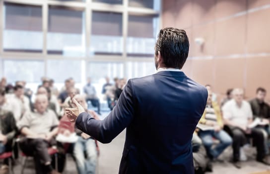 Speaker at Business Conference with Public Presentations. Audience at the conference hall. Entrepreneurship club. Rear view. Horisontal composition. Background blur.