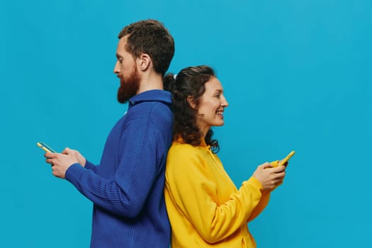 Woman and man cheerful couple with phones in their hands crooked smile cheerful, on blue background. The concept of real family relationships, talking on the phone, work online. High quality photo