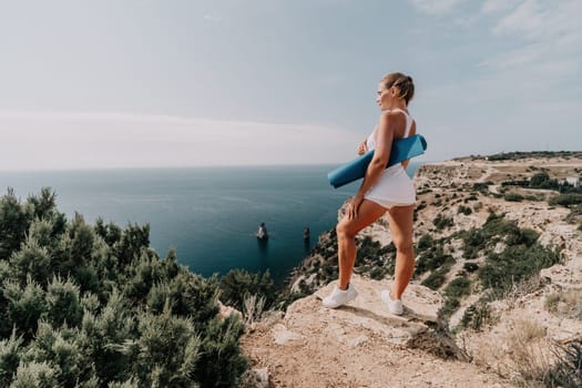 Middle aged well looking woman with black hair doing Pilates with the ring on the yoga mat near the sea on the pebble beach. Female fitness yoga concept. Healthy lifestyle, harmony and meditation.