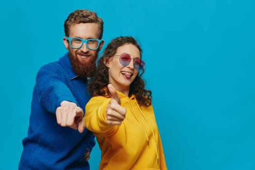 A woman and a man fun couple cranking and showing signs with their hands smiling cheerfully, on a blue background, The concept of a real relationship in a family. High quality photo