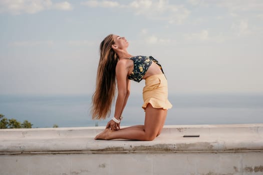 Woman park yoga. Side view of free calm bliss satisfied woman with long hair standing in morning park with yoga position against of sky by the sea. Healthy lifestyle outdoors in park, fitness concept