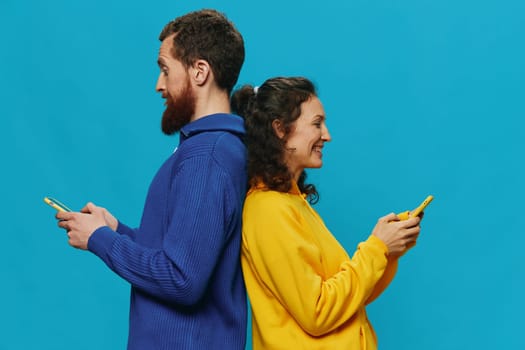 Woman and man cheerful couple with phones in their hands crooked smile cheerful, on blue background. The concept of real family relationships, talking on the phone, work online. High quality photo