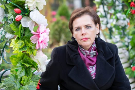 Portrait of a fifty-year-old woman with a short haircut in a black coat.