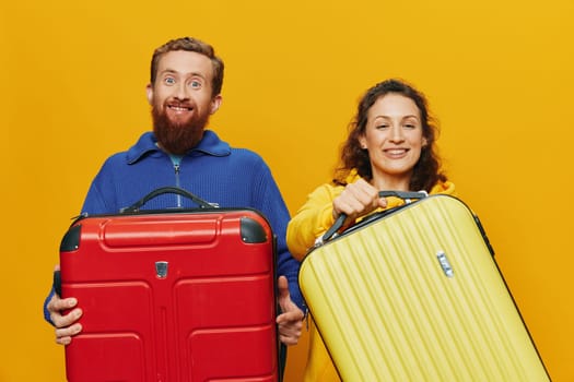 Woman and man smiling, suitcases in hand with yellow and red suitcase smiling merrily and crooked, yellow background, going on a trip, family vacation trip, newlyweds. High quality photo