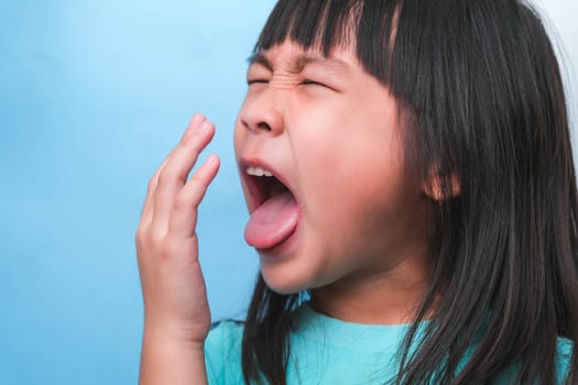 Little asian girl covering her mouth to smell the bad breath. Child girl checking breath with her hands. Oral health problems or dental care concept.