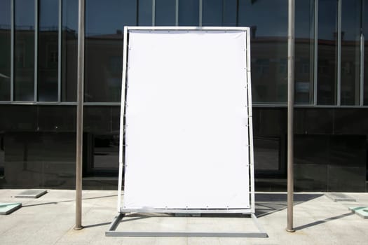 An empty advertising banner stands on a city street.